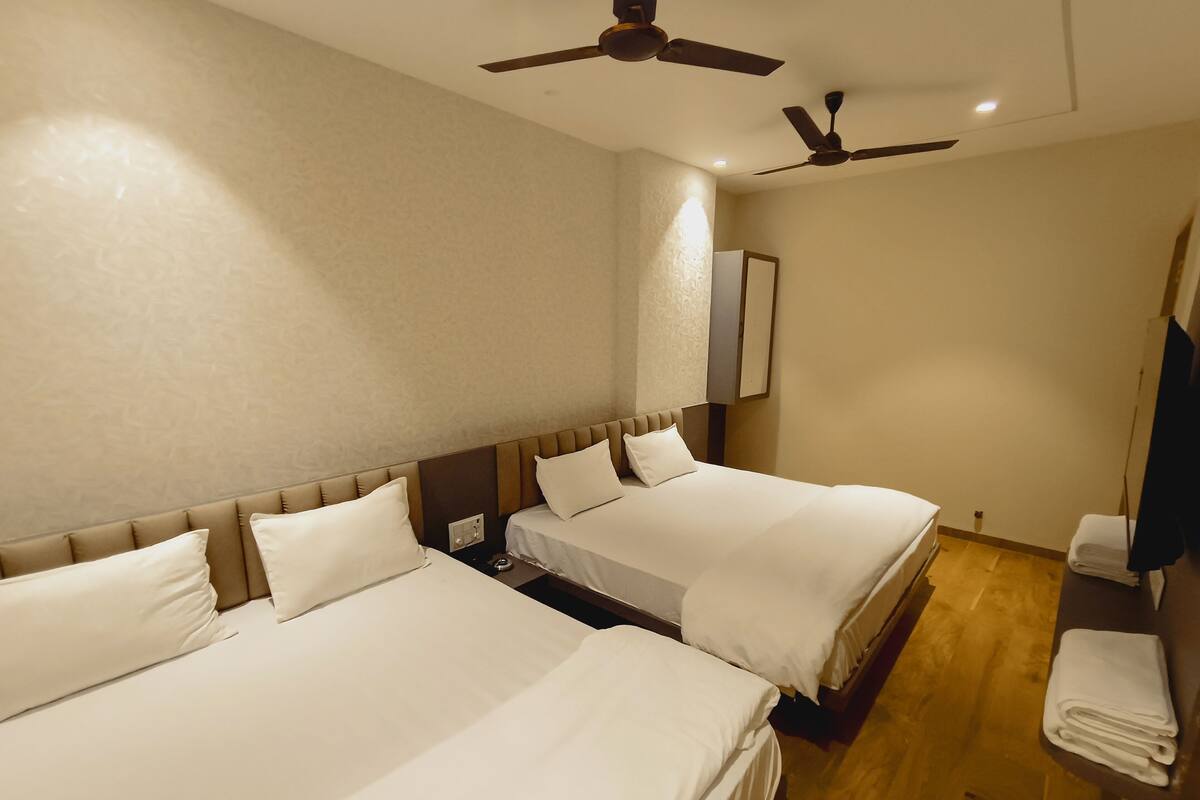 A hotel room with two beds, ceiling fans, a mirror, and a wooden floor.
