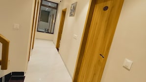 A hallway with wooden doors, a bench, and a mirror on the wall. - Rukkmannie Holiday Inn (Ujjain)