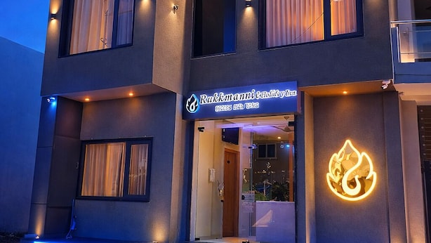 A modern two-story building with a glass facade, a neon sign, and a balcony. - Rukkmannie Holiday Inn (Ujjain)