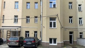 A multi-story building with a parking area. There are two cars parked in front. - Emma Apartments - Studio apartment for 1 guest (Hlavní město Praha)