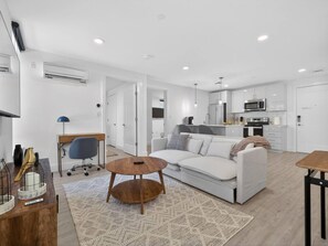 Ein modernes Wohnzimmer mit Sofa, Couchtisch und Schreibtisch mit Lampe.