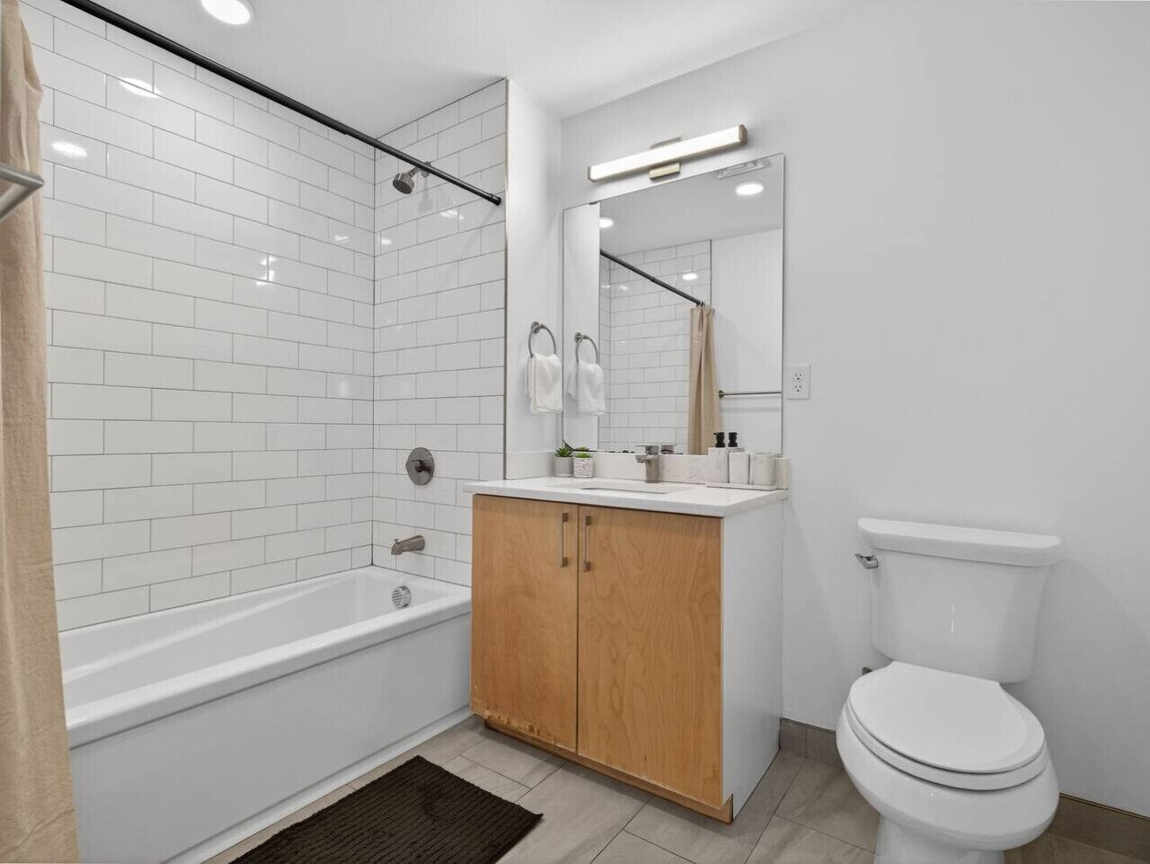 A bathroom with a white bathtub, wooden vanity, and a toilet.