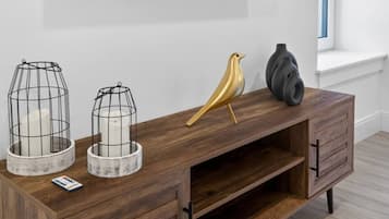 A wooden console table with two wire cage candle holders, a golden bird sculpture, and a black vase.