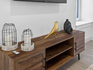 Ein Holzkonsolentisch mit zwei Kerzenhaltern aus Drahtgitter, einer goldenen Vogelstatue und einer schwarzen Vase.