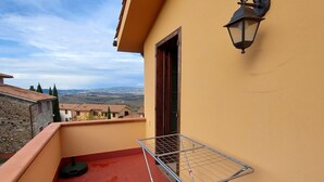 Un balcon doté d’un étendoir métallique, d’une lampe fixée au mur et offrant une vue sur des bâtiments éloignés.