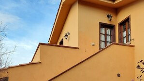 Un bâtiment à la façade jaune, avec un escalier menant à l’entrée et un extincteur fixé au mur.