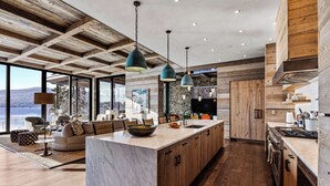Une cuisine moderne dotée d’un grand îlot central, de meubles en bois et de luminaires suspendus.