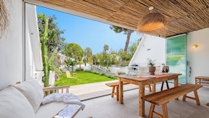 A modern interior with a wooden dining table, benches, and a white sofa. - Fantastic garden apartment directly on the dream beach of Puerto Alcudia (Alcúdia)