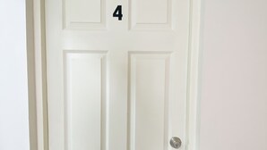 Una porta blanca amb el número 4, una clau i un pom de porta.