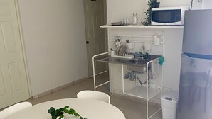 Cuina amb taula blanca, cadires, ventilador de sostre, microones i nevera.
