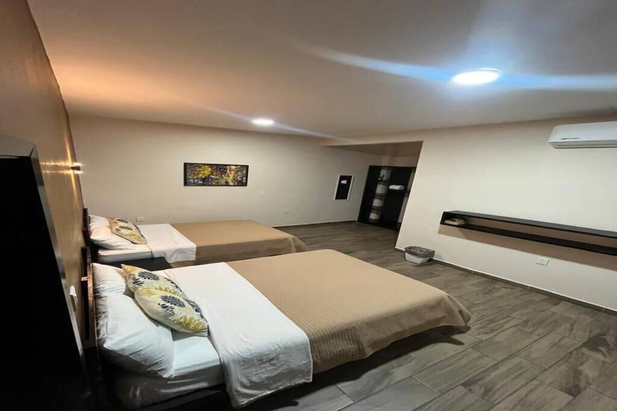 Ein Hotelzimmer mit zwei Betten, einem Fernseher, einem Bild an der Wand und einer Klimaanlage.