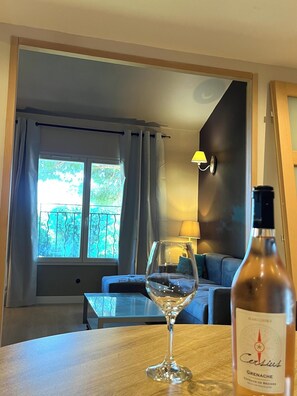 A room with a table, a wine glass, and a bottle of Côtes de Béziers wine. - Apartment 70 m2 pool property, parking, sea 4 km (Sérignan)