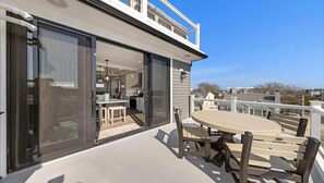 Patio esterno moderno con tavolo e sedie rotonde, una porta vetrata che dà su uno spazio interno e vista libera sul quartiere circostante.
