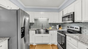 A kitchen with white cabinets, a stainless steel refrigerator, a microwave, and a stove. - Sleeps 6 | Private Patio | Near Downtown CHS (North Charleston)
