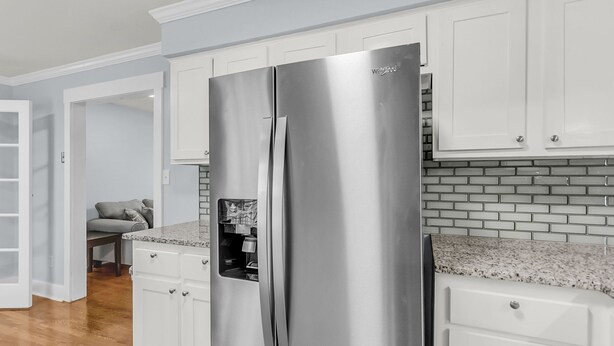 A kitchen with white cabinets, a stainless steel refrigerator, and a granite countertop. - Sleeps 6 | Private Patio | Near Downtown CHS (North Charleston)