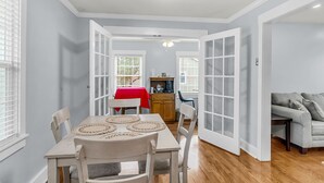 A dining area with a table, chairs, and a red tablecloth. There is a kitchen area with cabinets and a countertop. - Sleeps 6 | Private Patio | Near Downtown CHS (North Charleston)
