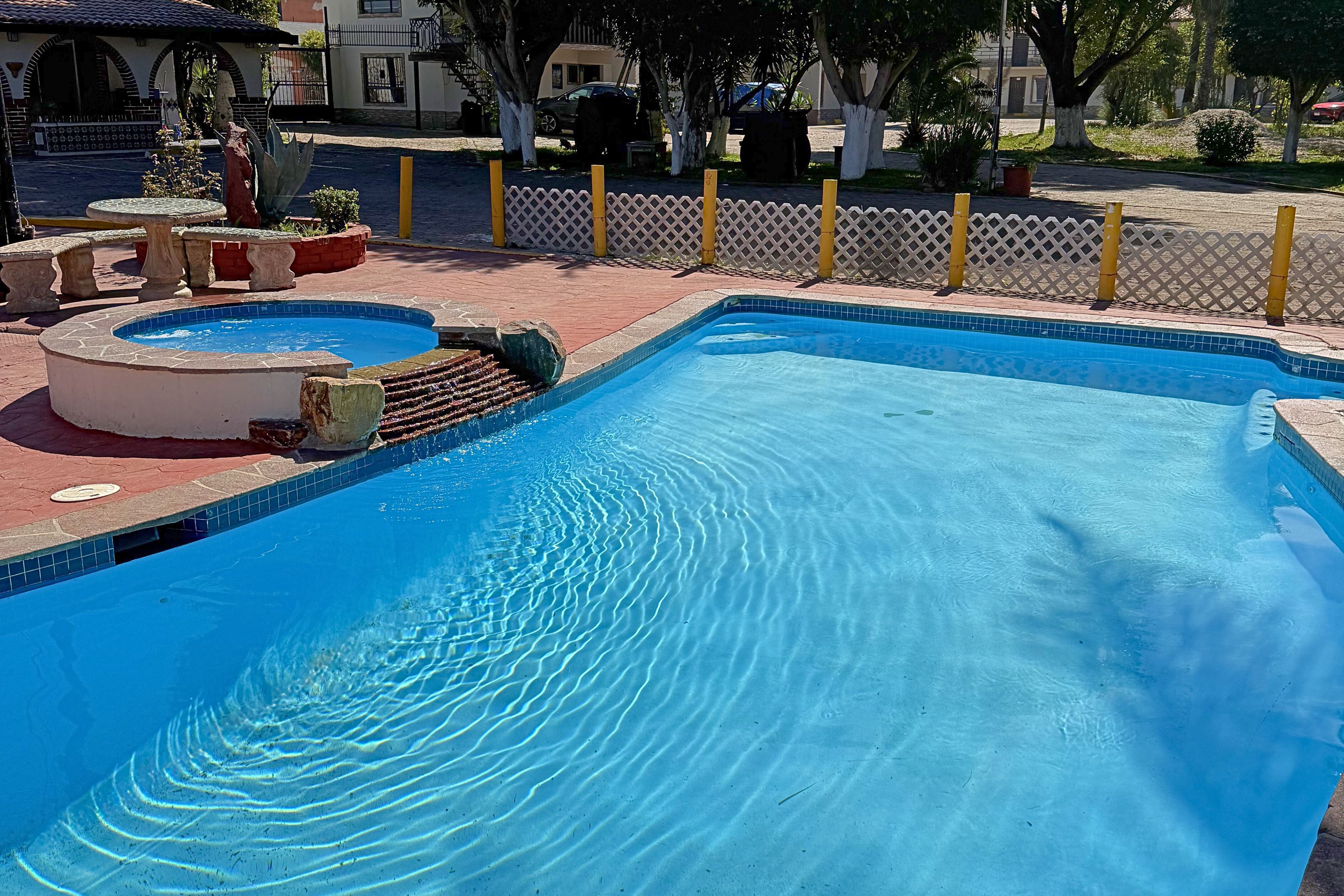 Una piscina con un pequeño jacuzzi y un borde de piedra.