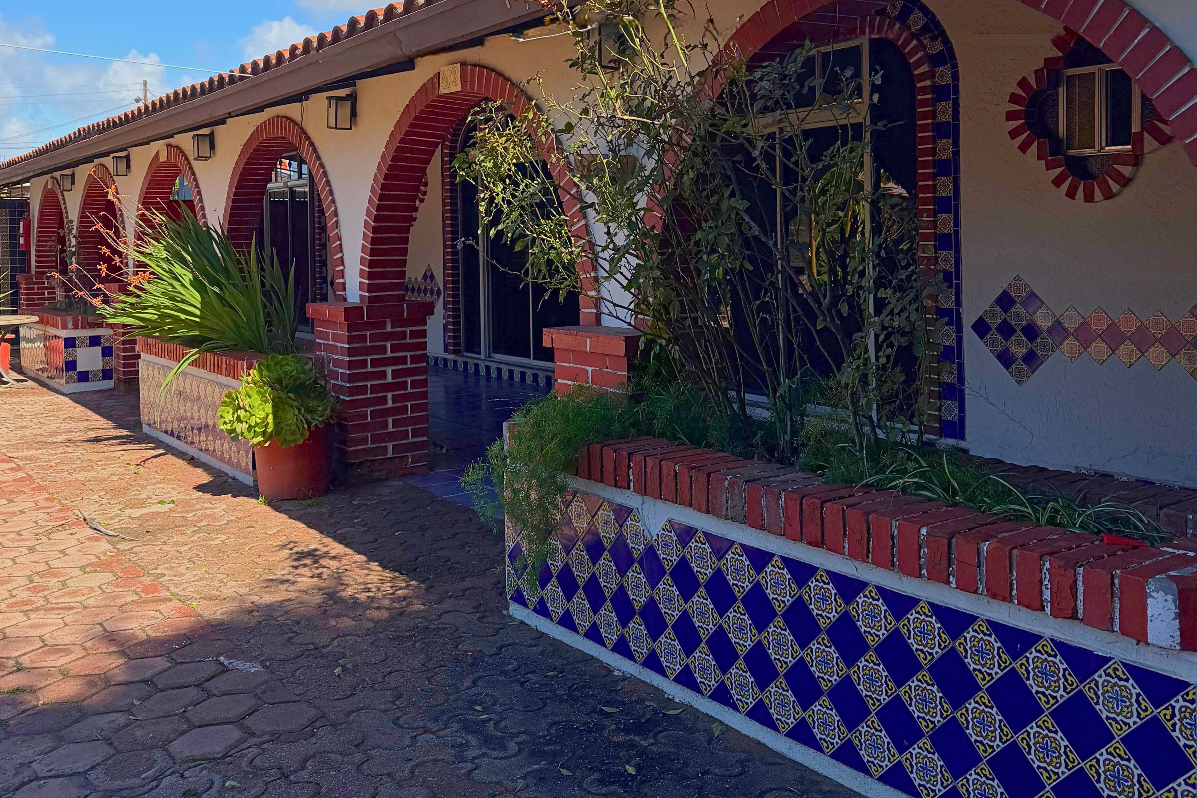 Un edificio con fachada de tejas, ventanas de arco y un camino adoquinado.