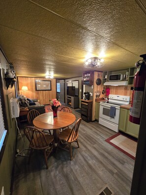Une cuisine compacte comprenant une table à manger, des chaises, un four à micro-ondes, une cuisinière et un réfrigérateur.