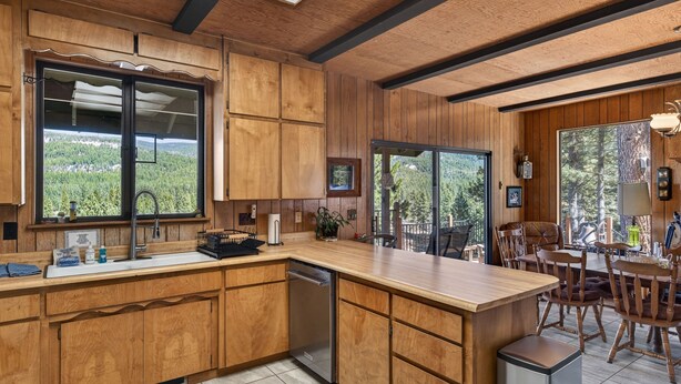 Eine moderne Küche mit Holzschränken, einer großen Kochinsel und Blick auf den Wald.
