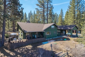 A two-story house with a fenced patio, a covered outdoor seating area, and a driveway. - Mountain Riverview Cliff House in The Lost Sierra (Graeagle)