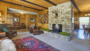 Ein rustikaler Innenraum mit Kamin aus Stein, Holzmöbeln und einer Bücherwand.
