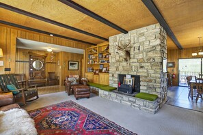 Un interior rústico con chimenea de piedra, muebles de madera y una estantería.