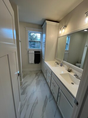 Une salle de bain avec un double vasque, un grand miroir et une fenêtre.