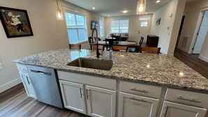 A kitchen with granite countertops, white cabinetry, and a central island.