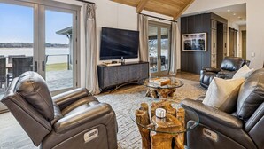 A spacious living room with a large TV, leather sofas, a glass coffee table, and a view of the outdoors. - Four bedroom  in United States of America, Winchester (Winchester)