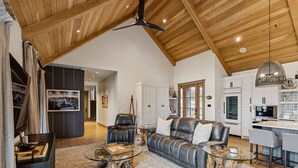 A spacious living area with a high ceiling, leather sofas, a glass coffee table, and a kitchen in the background. - Four bedroom  in United States of America, Winchester (Winchester)