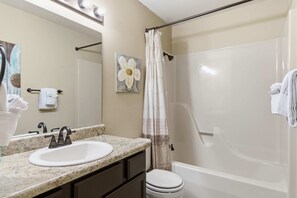 A bathroom with a sink, mirror, shower curtain, and toilet. - Overlook Paradise  Scenic Stay (Branson)