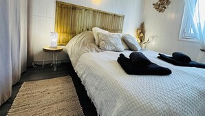 Ett sovrum med en säng, ett sängbord, en lampa och en dekorativ väggdekoration.