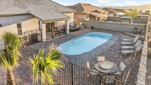 A backyard with a swimming pool, patio furniture, and a covered seating area. - Sunset Pool Home Retreat Sleeps 11 Close to River (Bullhead City)