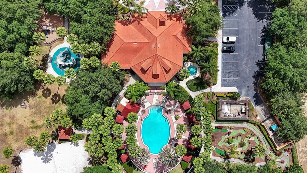 Vista aérea de un complejo turístico con una piscina central, varias habitaciones para huéspedes y un estacionamiento.