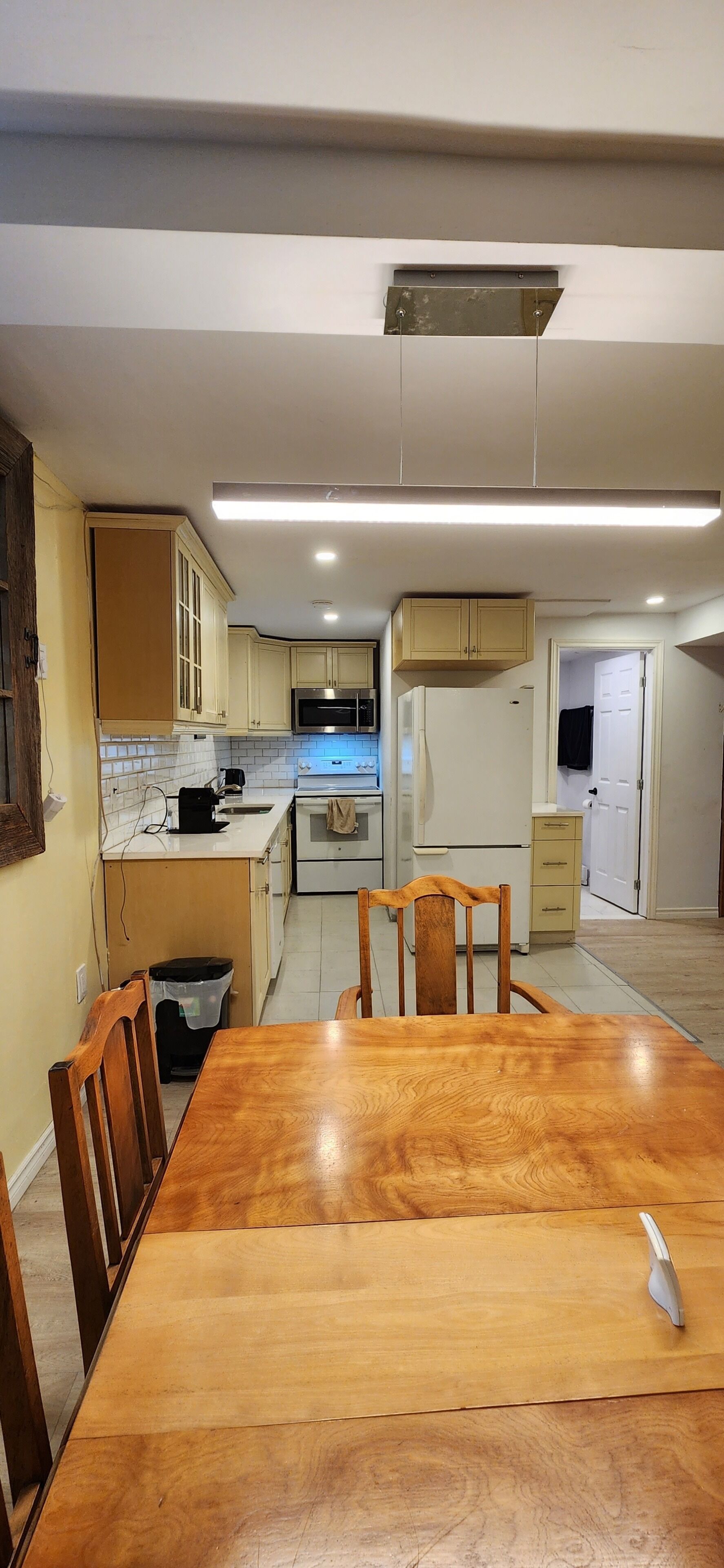 A kitchen with white cabinets, a wooden dining table, and chairs.