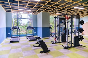 Ein Fitnessstudio mit Laufbändern, einer Hantelbank und Gewichtsplatten.
