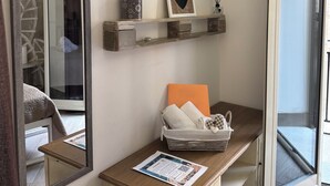 Ein Zimmer mit einem großen Spiegel, einem an der Wand montierten Fernseher, einer kleinen Ablage mit Dekoration und einer Glastür, die sich öffnen lässt.