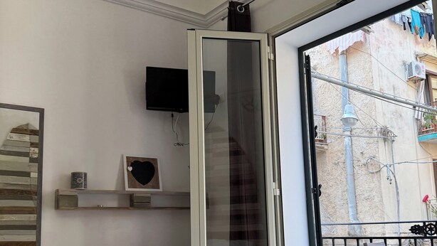 Ein Hotelzimmer mit Bett, Fernseher, Balkon mit Stadtblick und Vorhängen am Fenster.