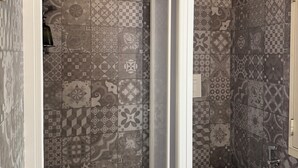 A bathroom with patterned tiles, a toilet, a shower area, and a hanging bag. - Foglie Road-Trip Base - L'Angoletto Di Andrea, Carini (Carini)