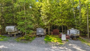 Un camping con vehículos recreativos, una cabaña de madera y un camino de grava.