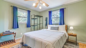 A bedroom with a bed, a nightstand, a ceiling fan, and a window with curtains. - Deck & Spacious Yard! Wilmington Gem on Half-Acre (Wilmington)