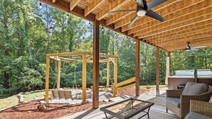 Un espacio de patio cubierto con una pérgola de madera, mobiliario exterior y un jacuzzi.