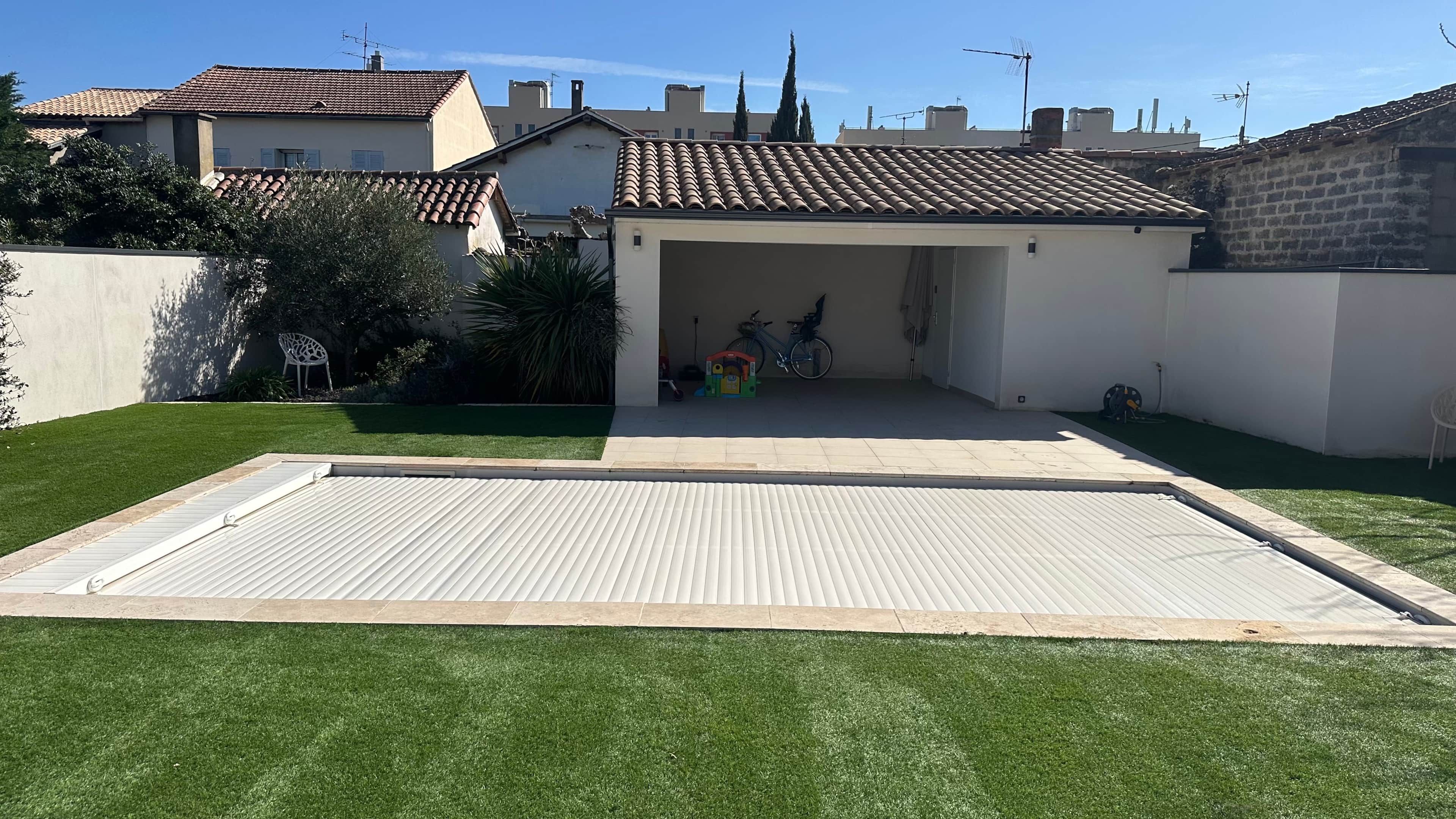Een woonhuis met een overdekte patio, een gazon en een bakstenen muur.
