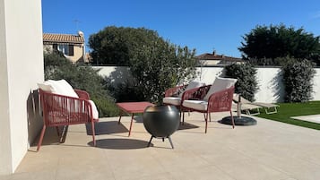 Une terrasse extérieure avec des chaises en osier, une table et un grand pot décoratif.