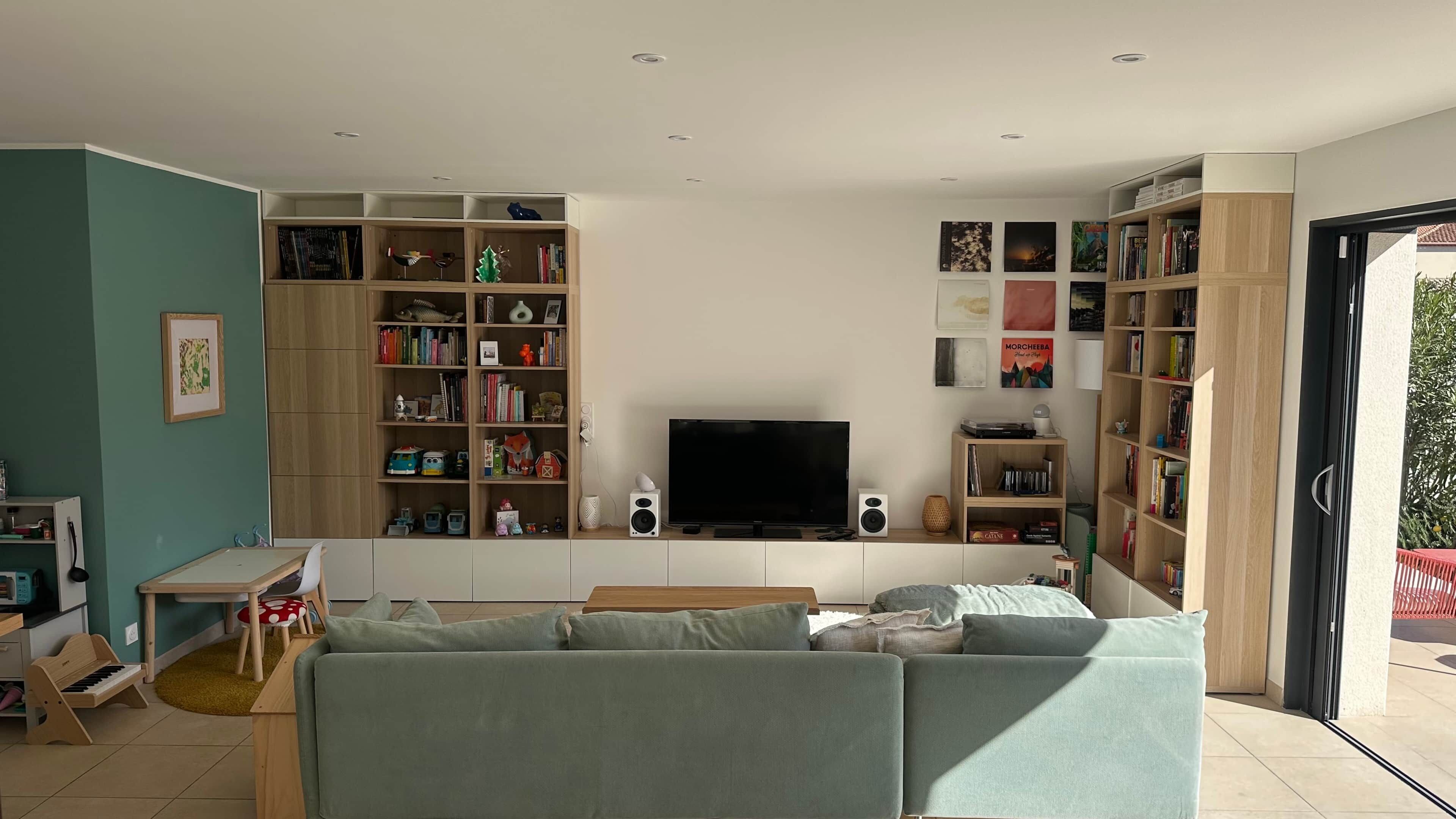 Un salon avec un canapé, un téléviseur, des étagères et une petite table.