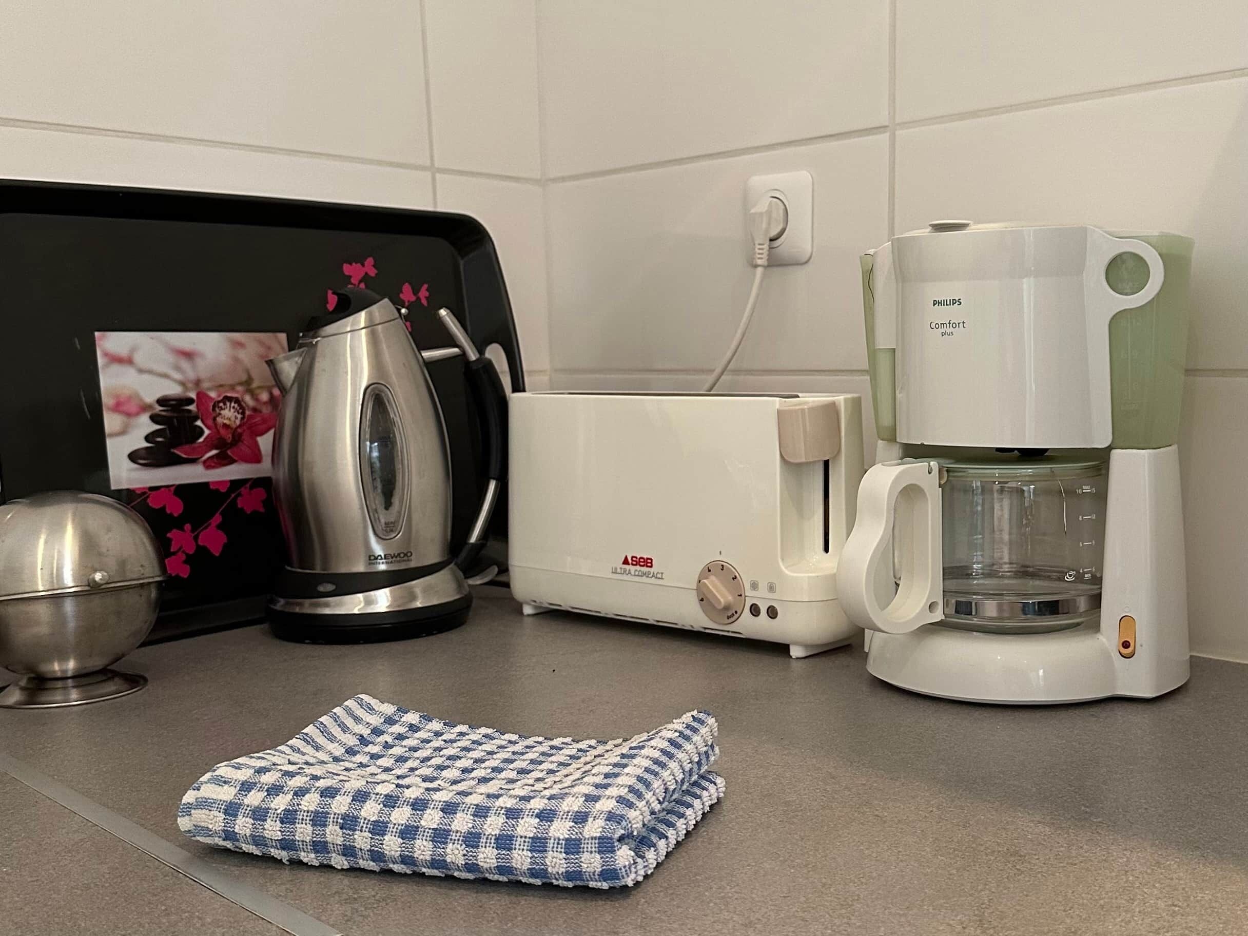 A kitchen with a coffee maker, a kettle, and a tea kettle.