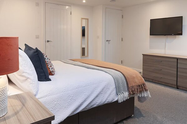 A bedroom with a bed, bedside table, dresser, TV, and wardrobe. - Prime Location 3BR with Garden (Cardiff)