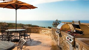 Patio esterno con pareti in pietra, un barbecue e un tavolo con sedie.