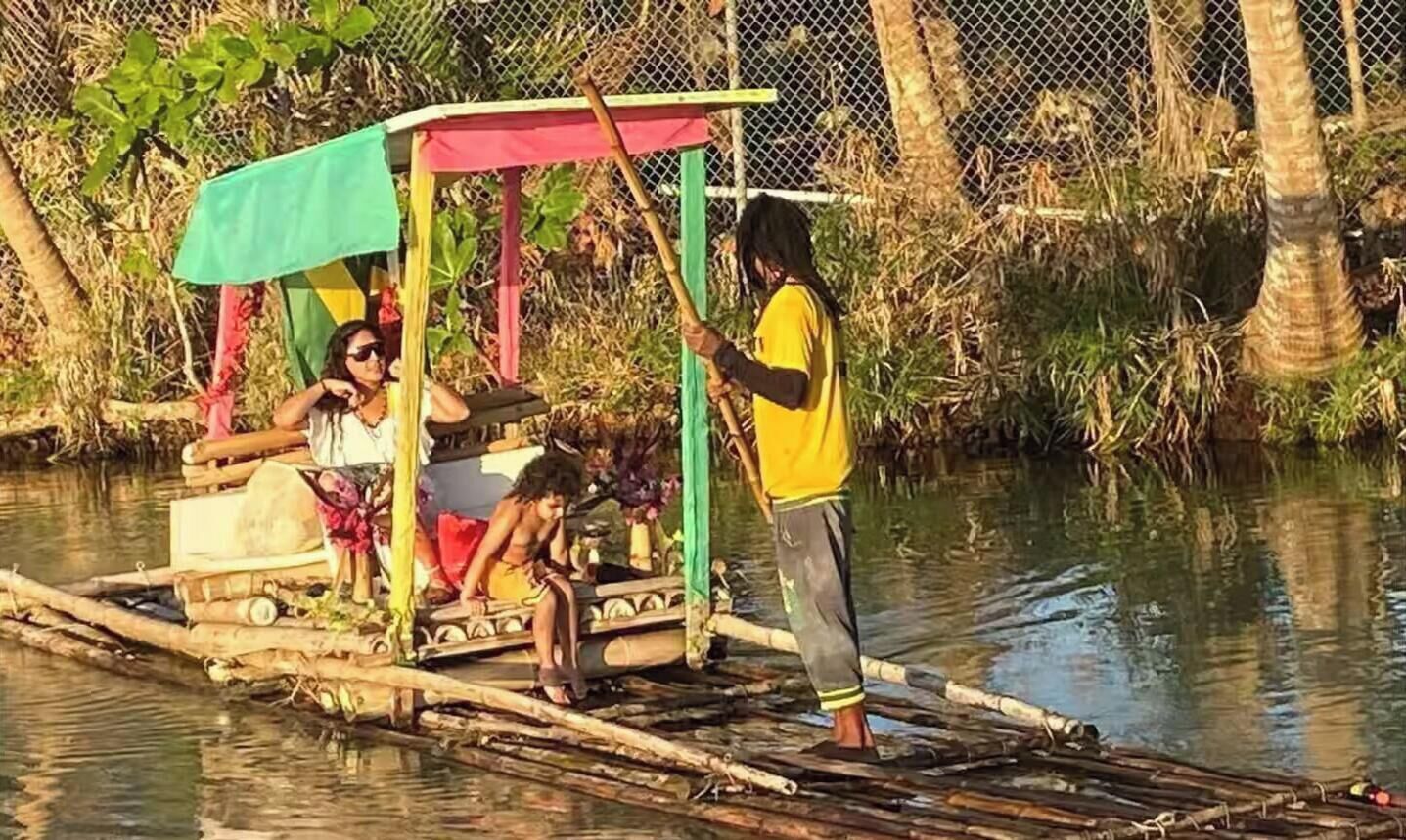 Un bote de madera con un toldo colorido, personas a bordo y una persona de pie en la orilla.